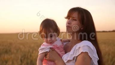 日落时分，母亲怀里抱着一个小孩子，带着<strong>麦子</strong>走在田<strong>野</strong>里。 慢动作。